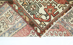 A folded vintage Persian rug featuring intricate geometric patterns in red, green, and cream.