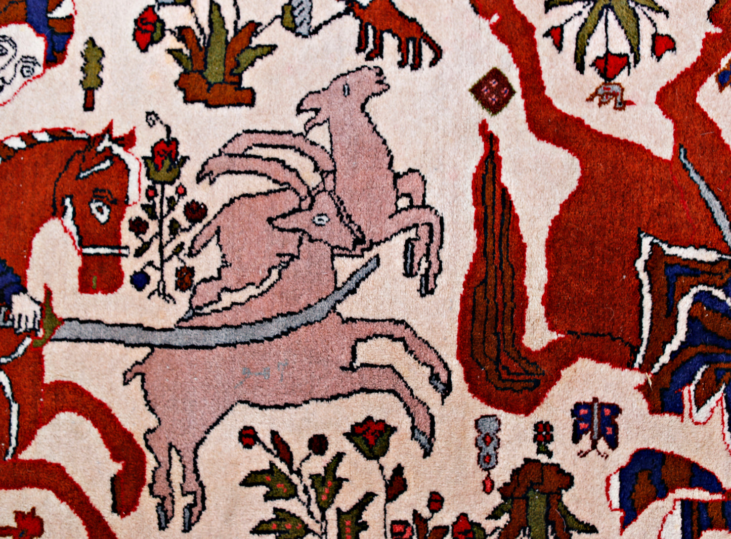 A vintage Persian rug featuring a detailed hunting scene with animals on a cream background.