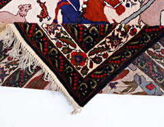 A vintage Persian rug with a hunting scene pattern, featuring a folded corner and fringe.