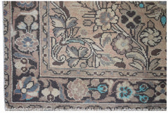 A vintage handwoven Persian rug featuring a floral pattern in muted tones with a fringed edge.