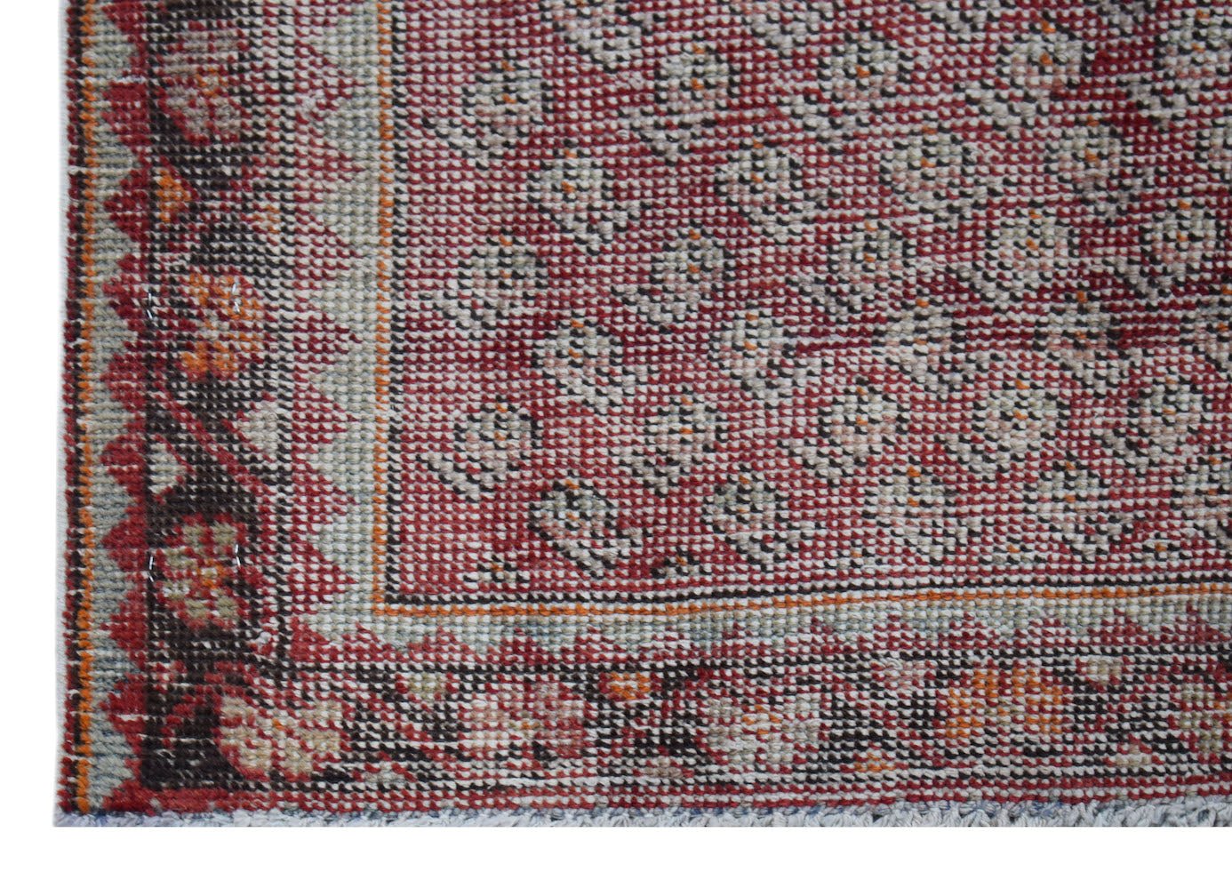 A handwoven vintage Persian rug featuring a red field with intricate patterns and a floral border.