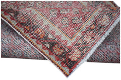 A handwoven vintage Persian rug featuring a red and cream geometric pattern on a wool pile.
