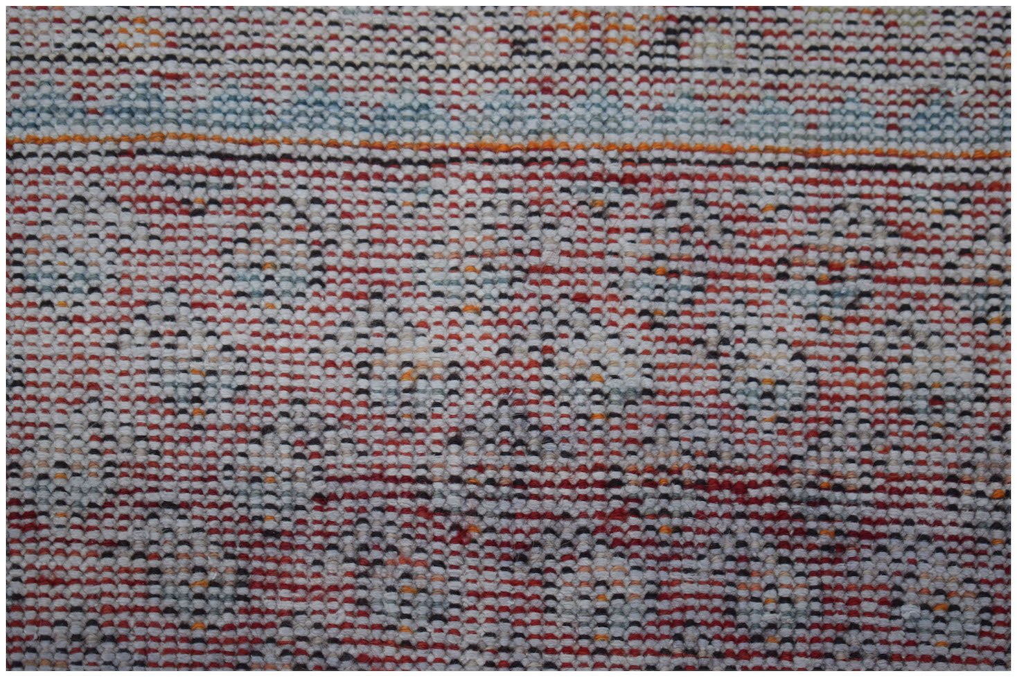 A vintage handwoven Persian rug featuring a repeating geometric pattern in red, white, and blue.