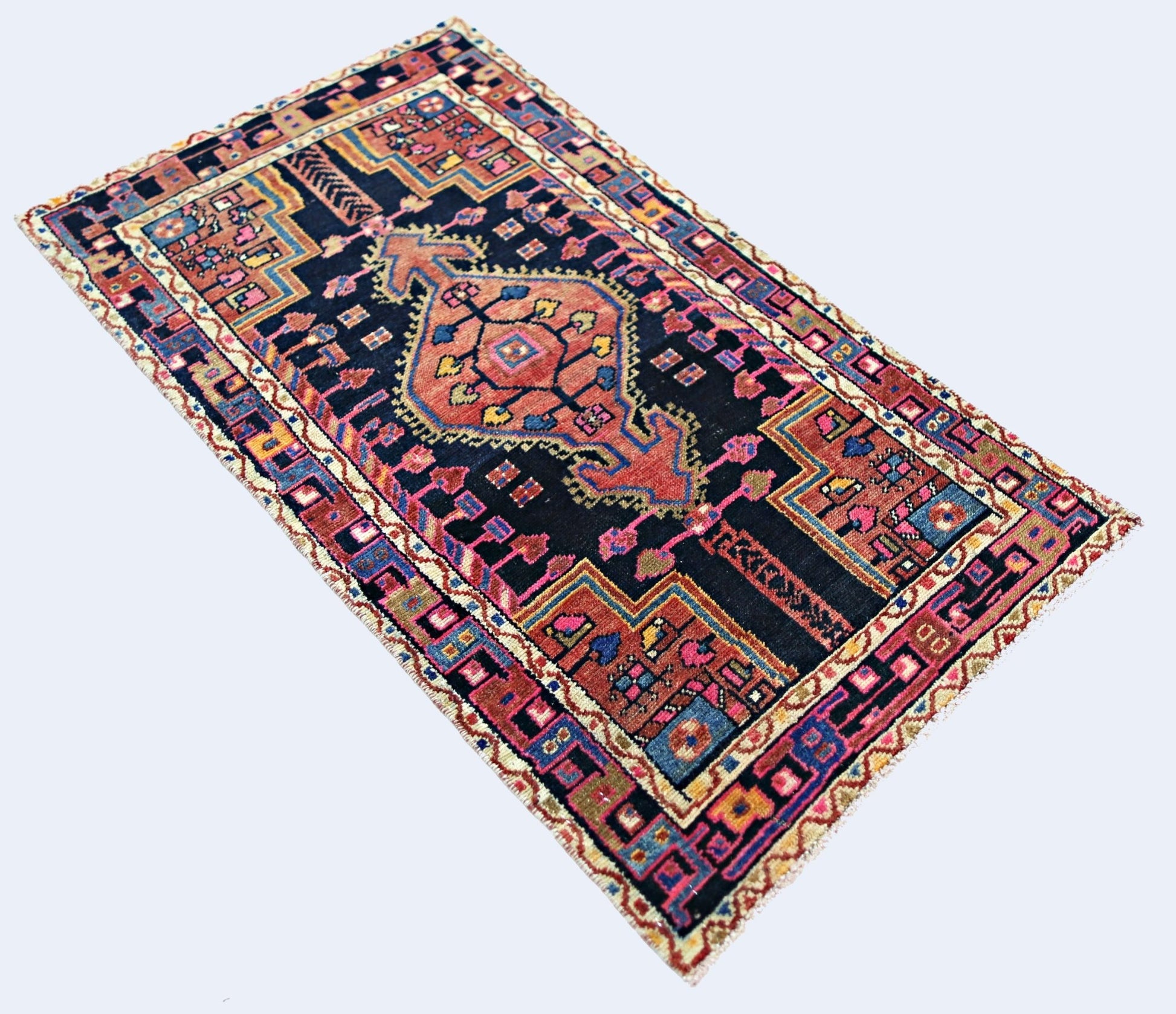A vintage Persian rug featuring a central geometric medallion on a dark blue field.
