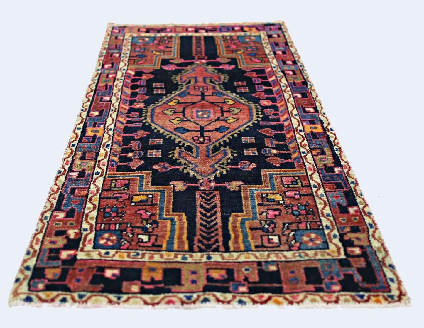 A vintage handmade Persian rug featuring a geometric medallion pattern in red, blue, and black.
