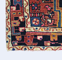 A corner view of a vintage handmade Persian rug featuring geometric patterns in red and blue.