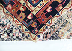 A corner of a vintage handmade Persian wool rug showing its intricate geometric pattern and weave.