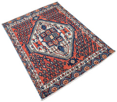 A handwoven vintage Persian rug featuring a central geometric medallion on a red and blue field.
