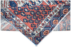 A handwoven vintage Persian rug featuring a geometric pattern in red, blue, and cream tones.