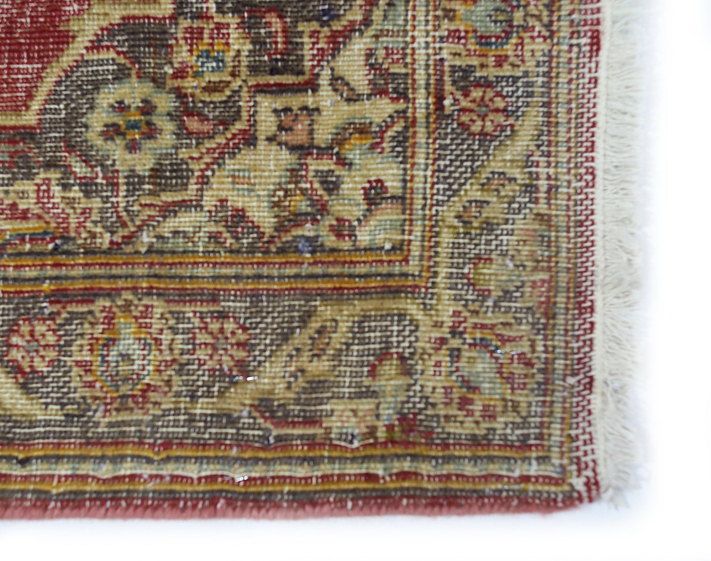 A close-up of a vintage Persian rug featuring intricate floral patterns in red, brown, and cream.