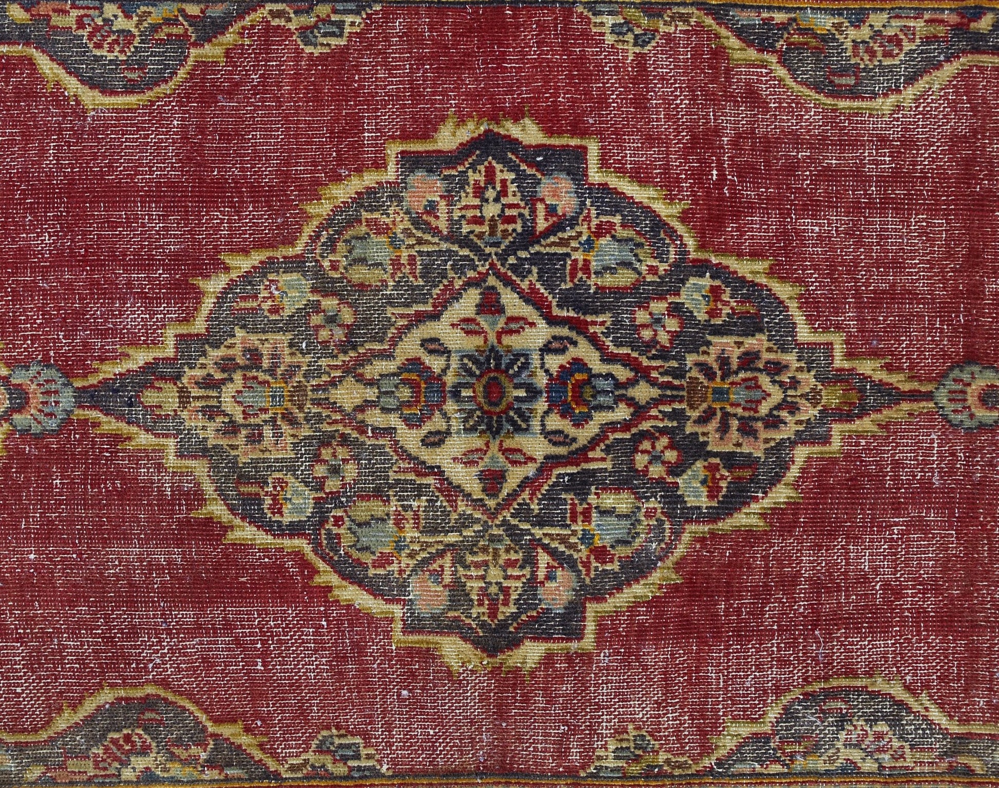 A vintage Persian rug featuring a central floral medallion in dark tones on a red field.