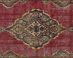 A vintage Persian rug featuring a central floral medallion in dark tones on a red field.