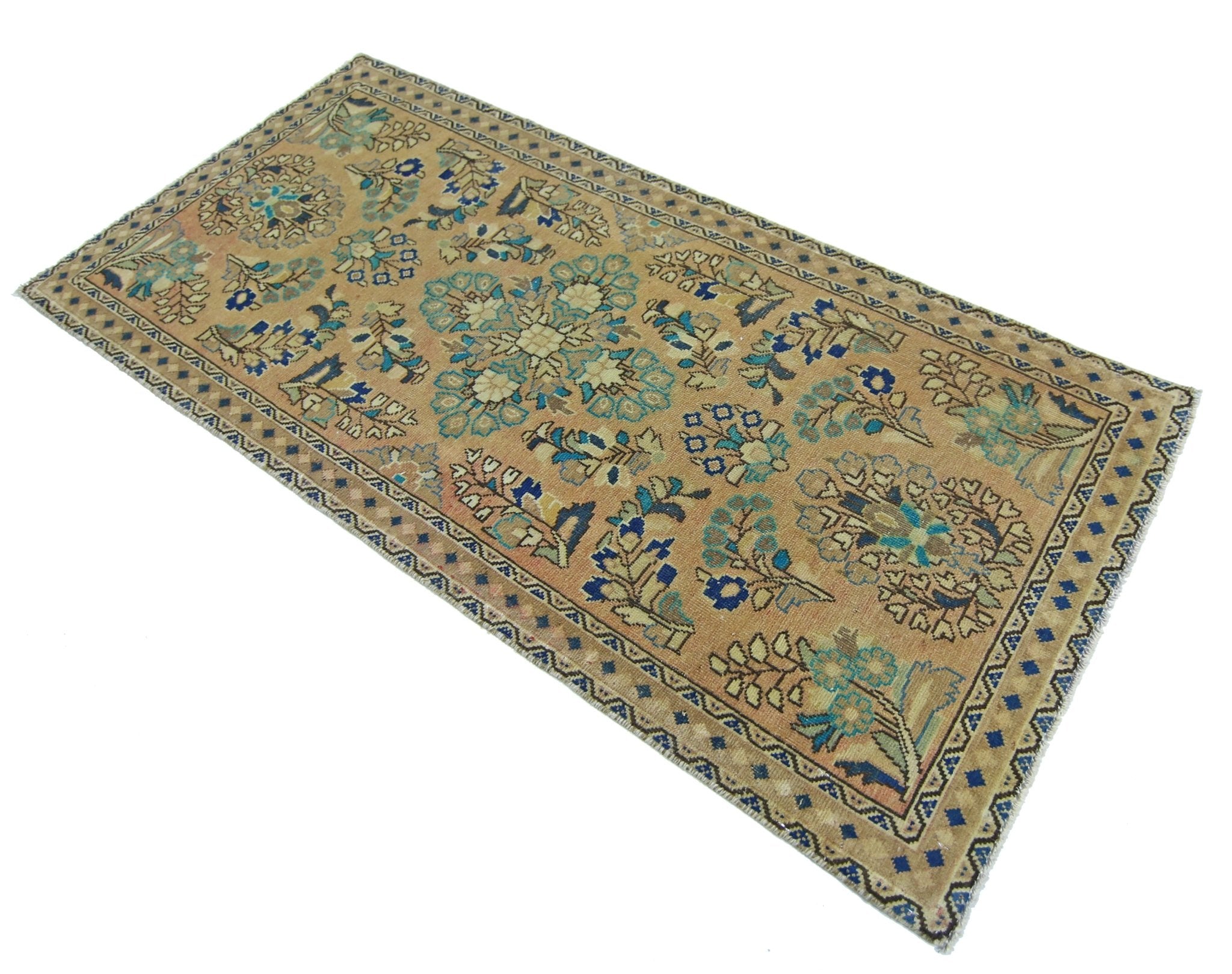 A vintage handmade Persian rug featuring a floral pattern in blue and tan on a wool pile.