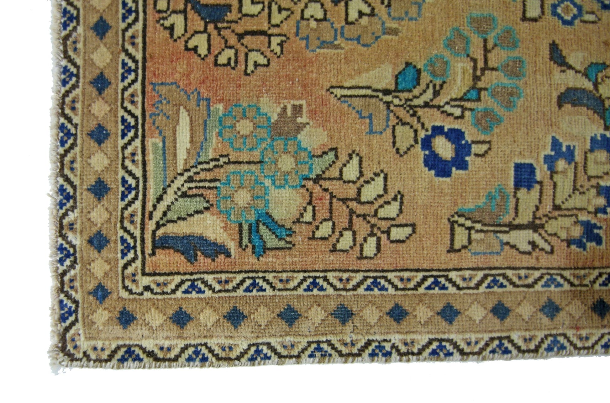 A vintage Persian rug featuring a floral pattern in blue and tan on an orange background.