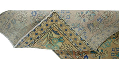 A folded vintage Persian rug featuring a floral pattern in muted blue and tan tones.
