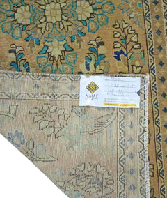 A vintage Persian rug with a tan field and blue floral patterns, shown with its underside visible.