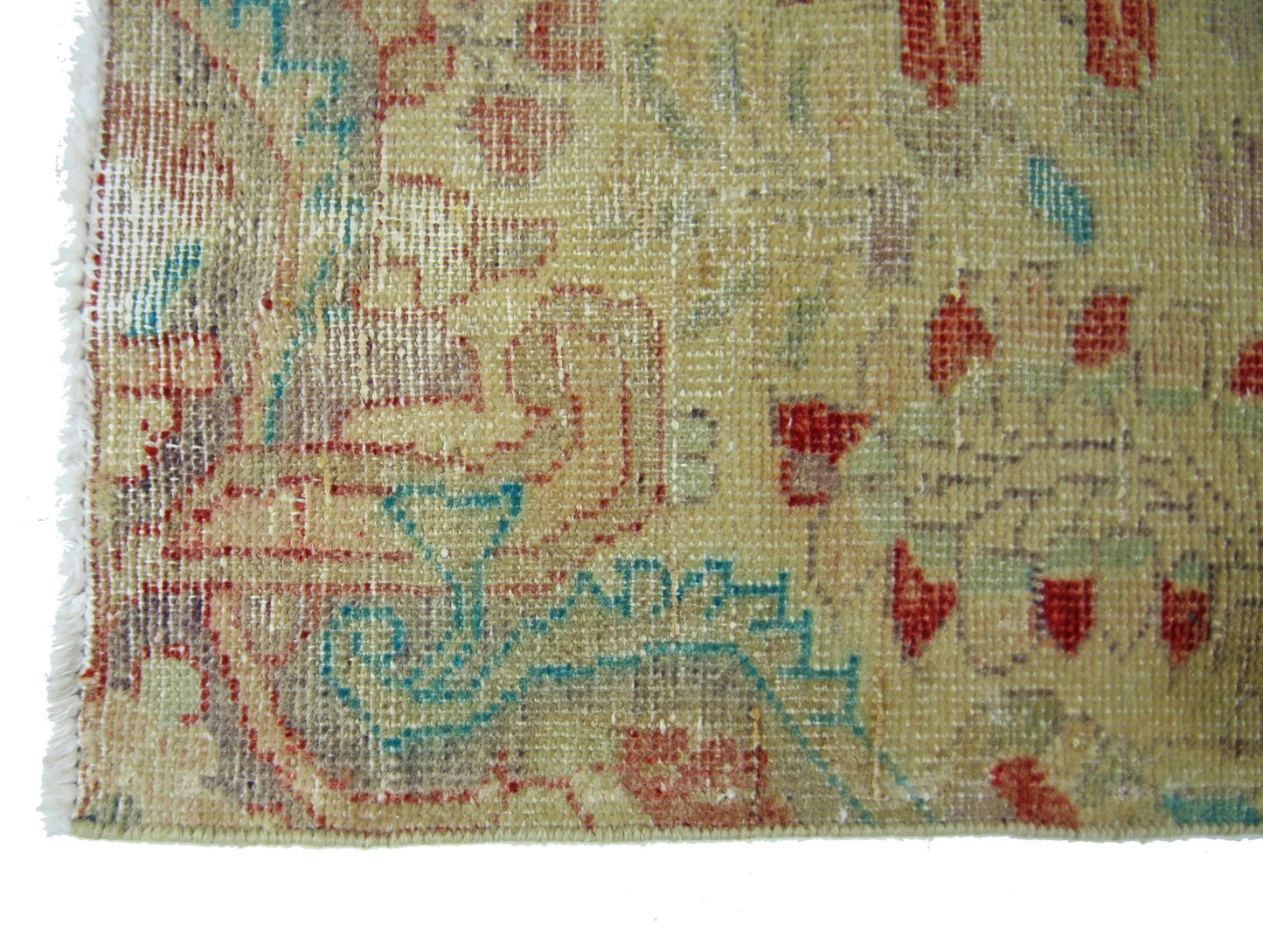 A vintage handmade Persian rug featuring a faded floral pattern in red, blue, and beige tones.