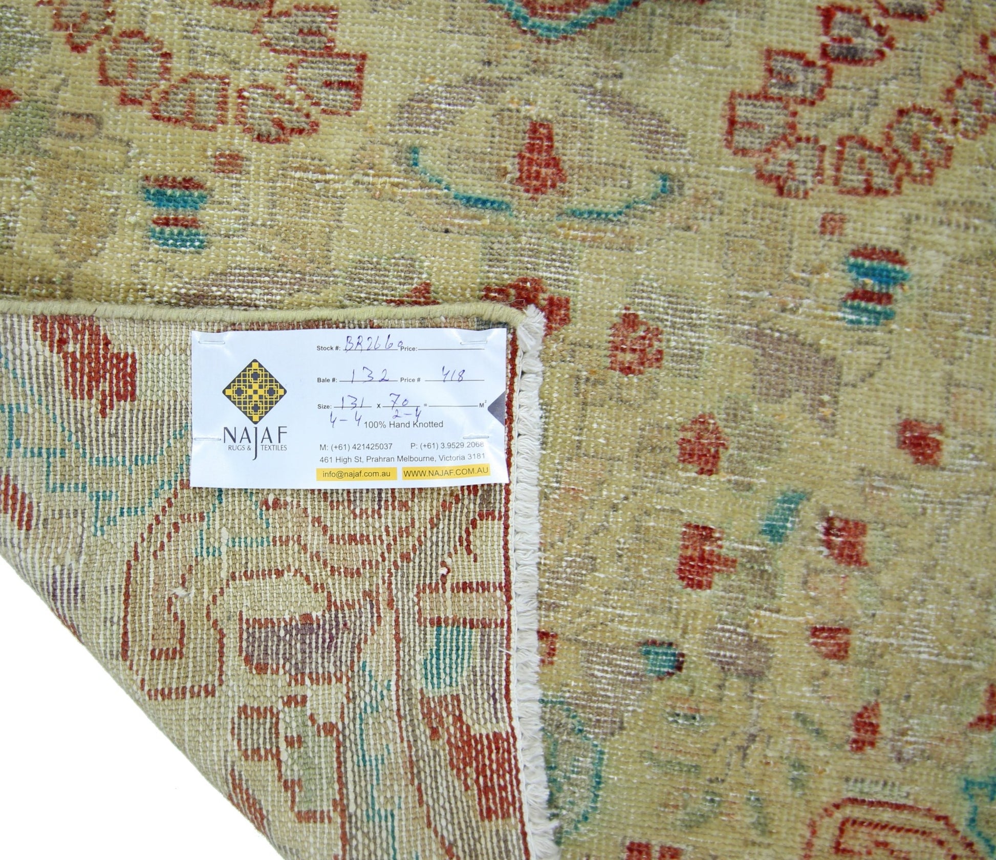 A vintage Persian rug with a faded floral pattern in red and green on a beige background.