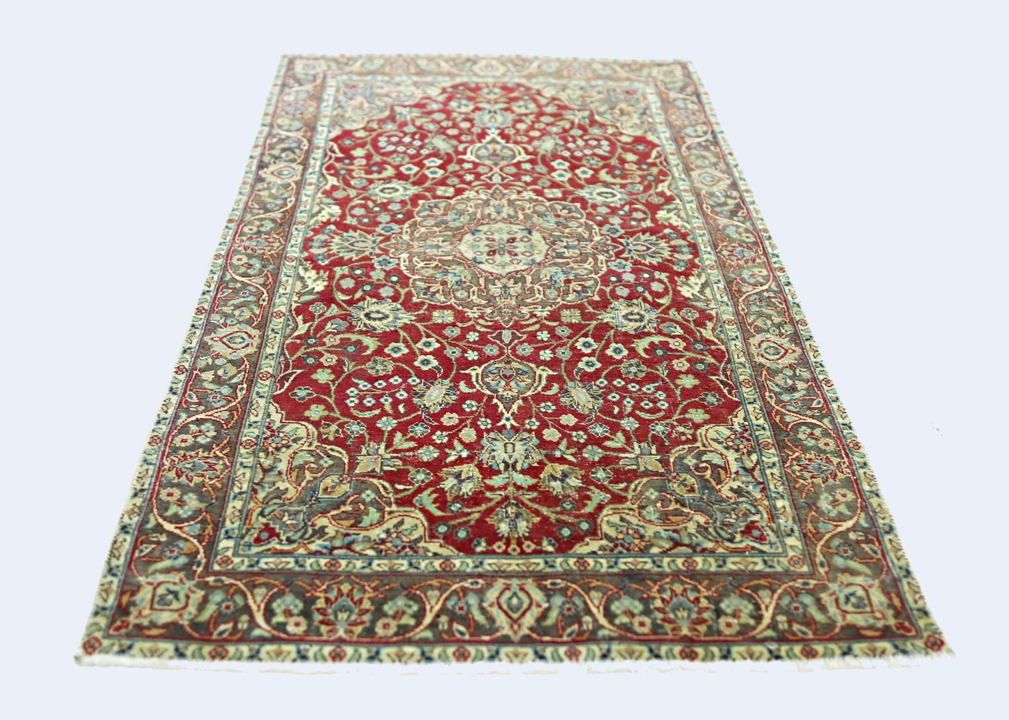 A vintage Persian rug featuring an intricate floral pattern in red, blue, and cream tones.