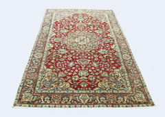A vintage Persian rug featuring an intricate floral pattern in red, blue, and cream tones.