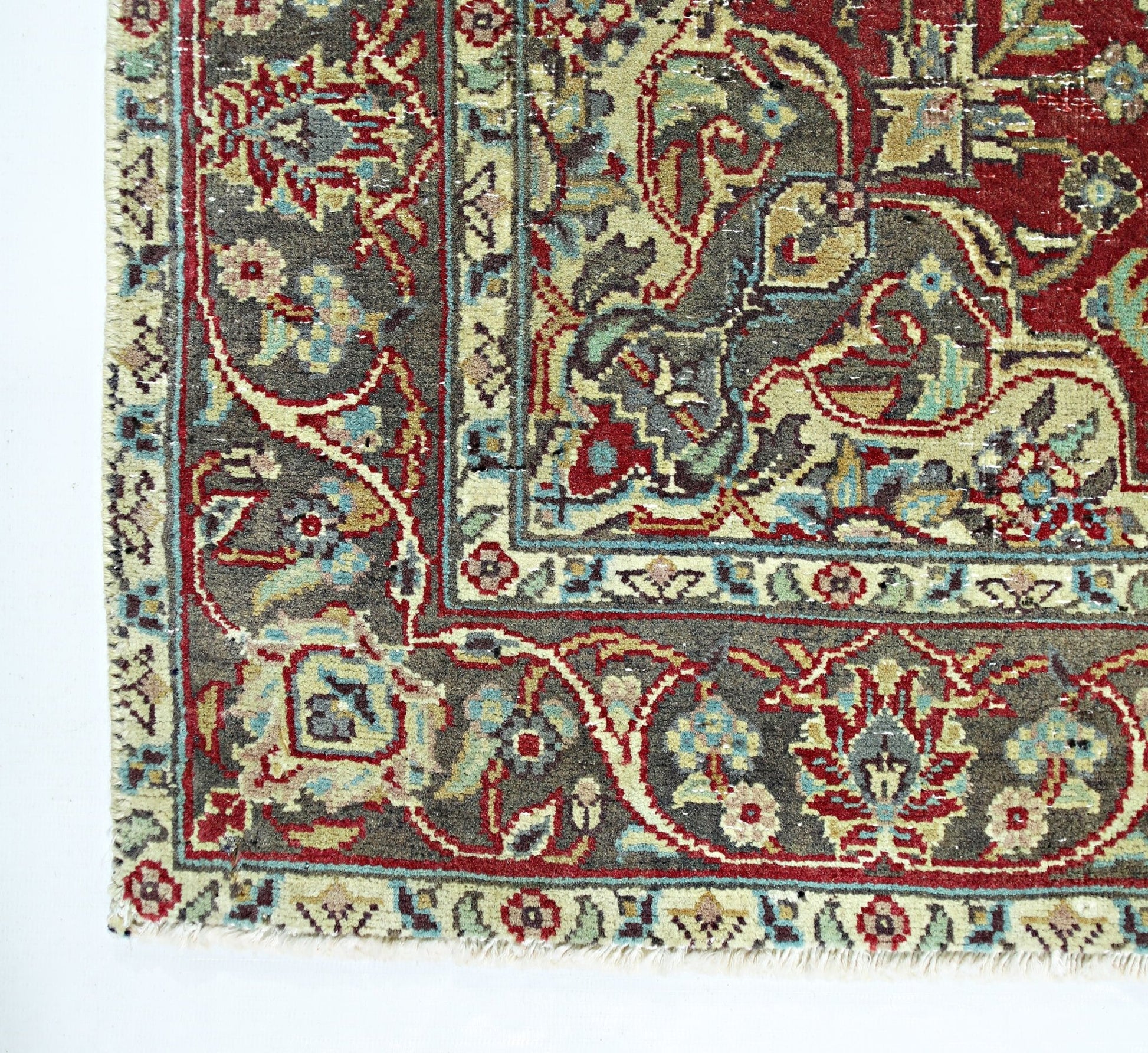 A vintage Persian rug featuring intricate floral patterns in red, blue, and beige on a dark field.