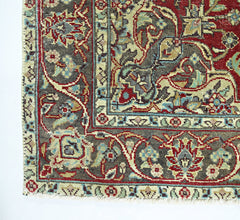 A vintage Persian rug featuring intricate floral patterns in red, blue, and beige on a dark field.