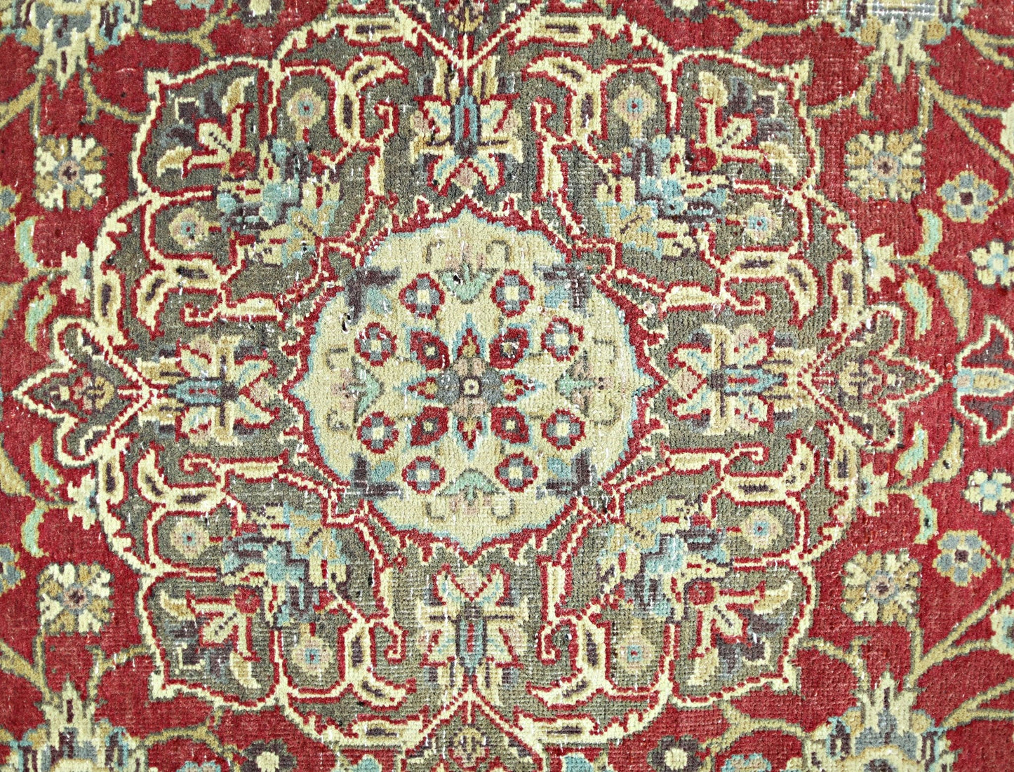 A vintage Persian rug featuring an intricate floral medallion pattern in red, beige, and blue.