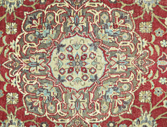 A vintage Persian rug featuring an intricate floral medallion pattern in red, beige, and blue.