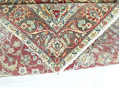 A folded vintage Persian rug featuring intricate floral patterns in red, blue, and beige tones.
