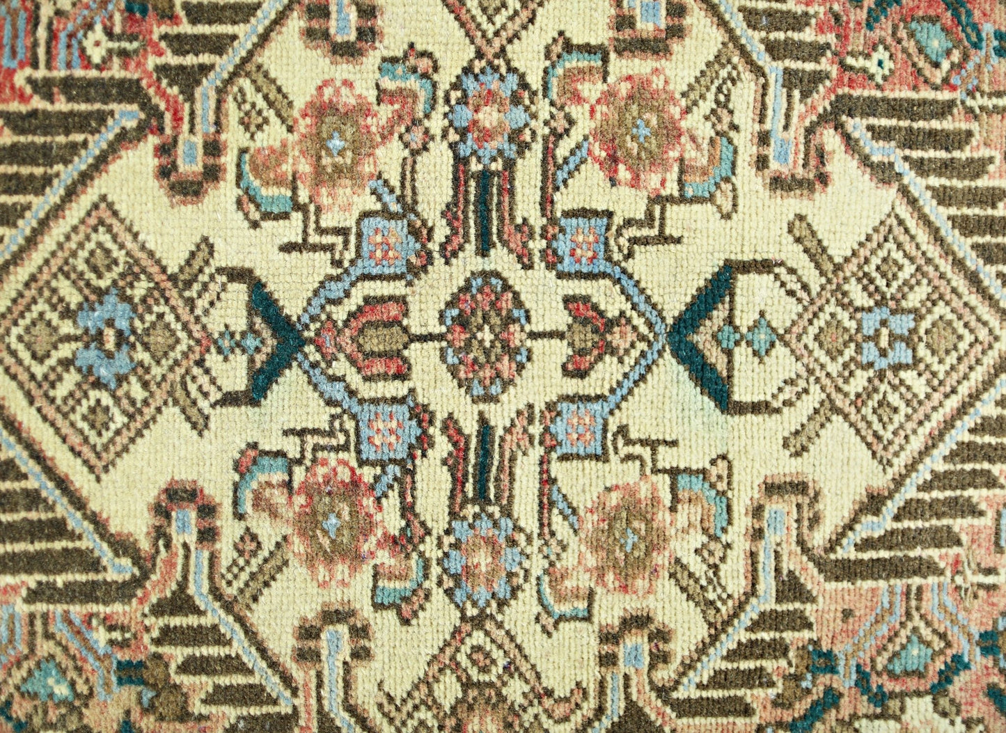 A vintage Persian rug featuring a detailed geometric floral pattern in cream, blue, and brown.