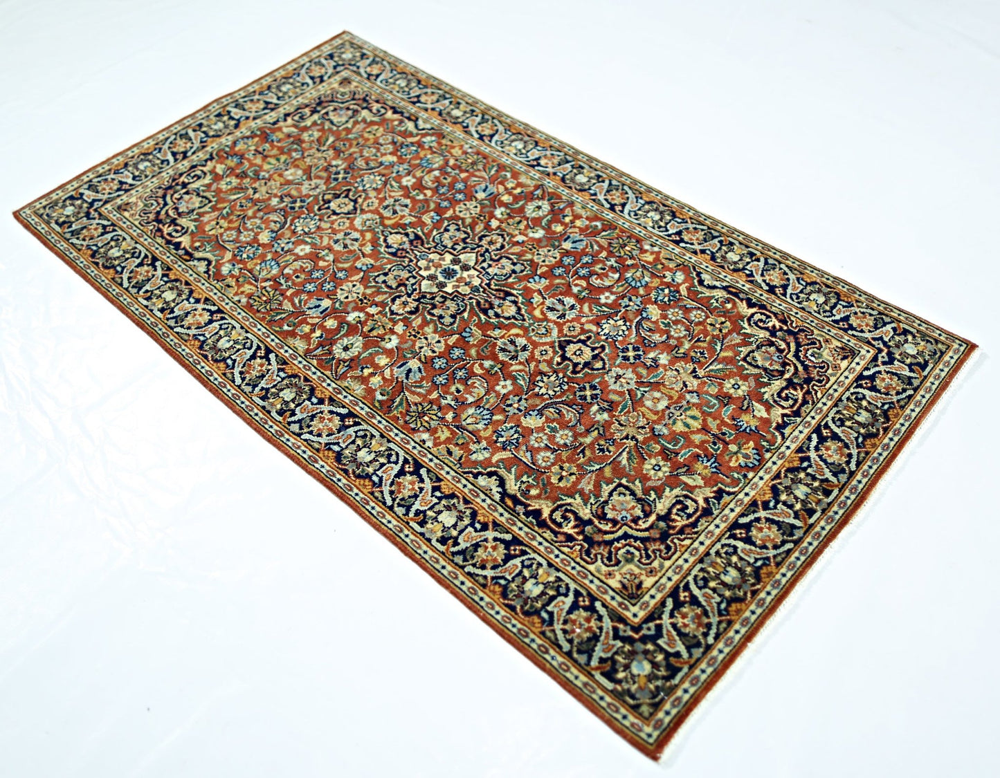 A rectangular vintage Persian rug featuring an intricate floral pattern in red, blue, and cream.