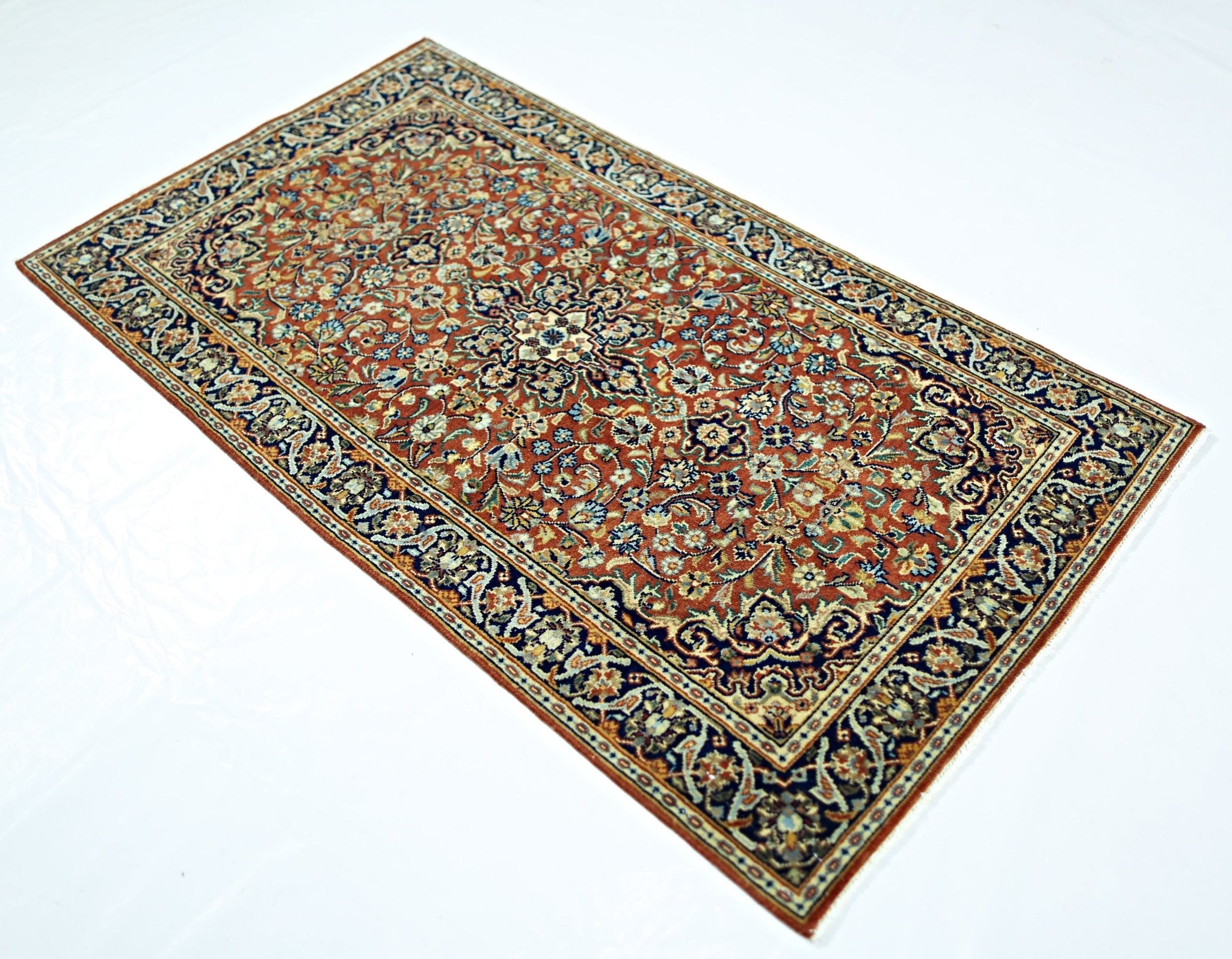 A rectangular vintage Persian rug featuring an intricate floral pattern in red, blue, and cream.