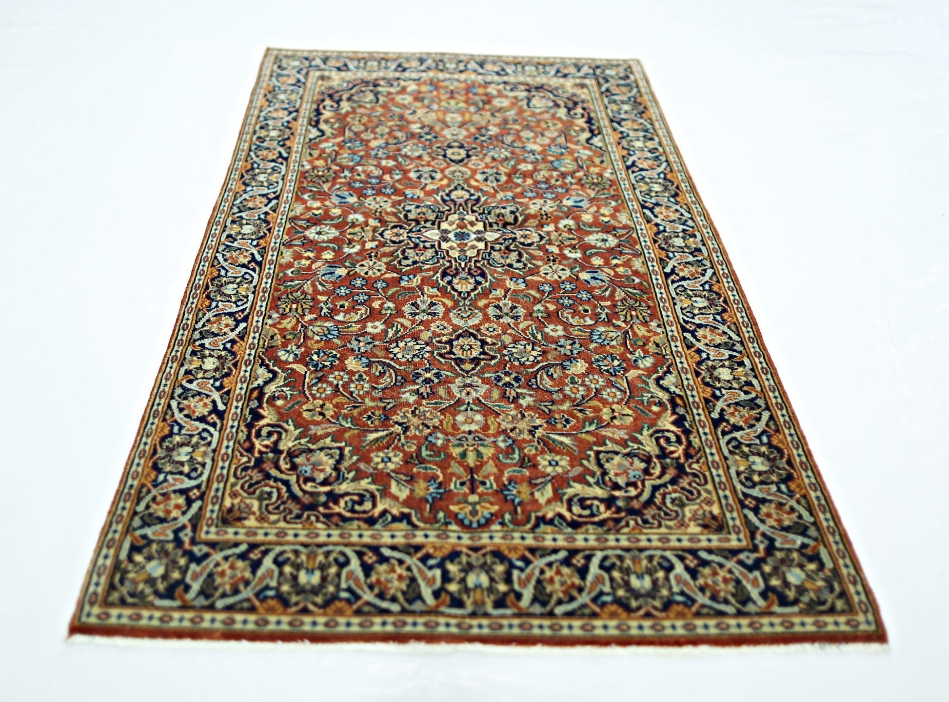 A rectangular vintage Persian rug featuring an intricate floral pattern in red, blue, and cream.