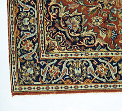 A corner view of a vintage Persian rug featuring intricate floral patterns in red, blue, and cream.