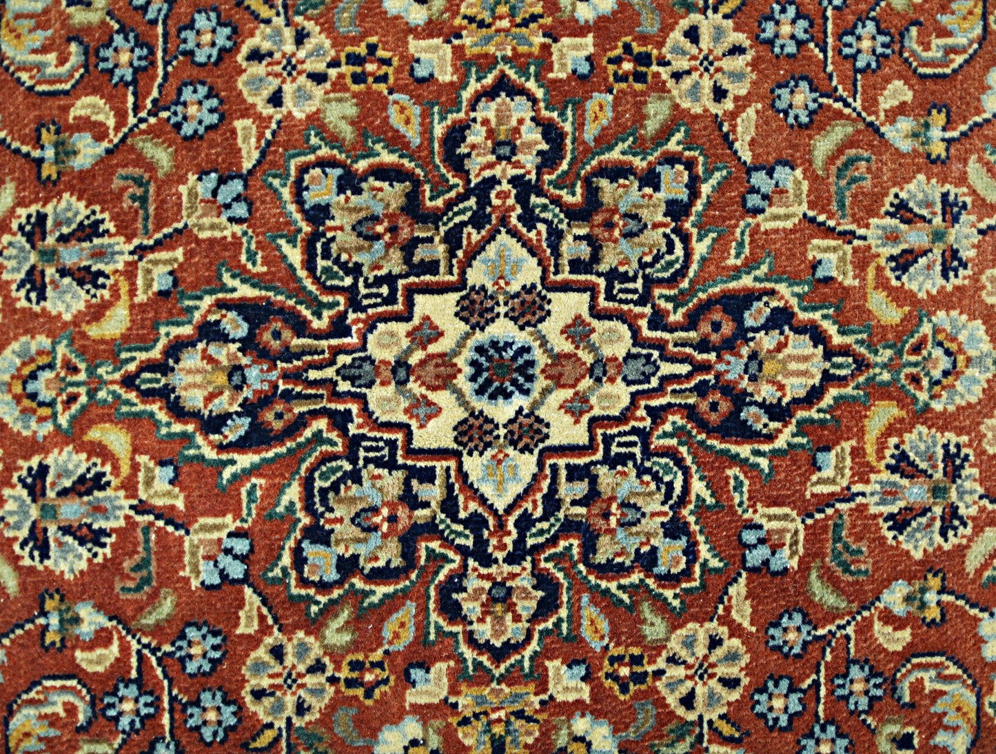 A vintage Persian rug featuring a detailed floral medallion pattern in shades of red, blue, and cream.
