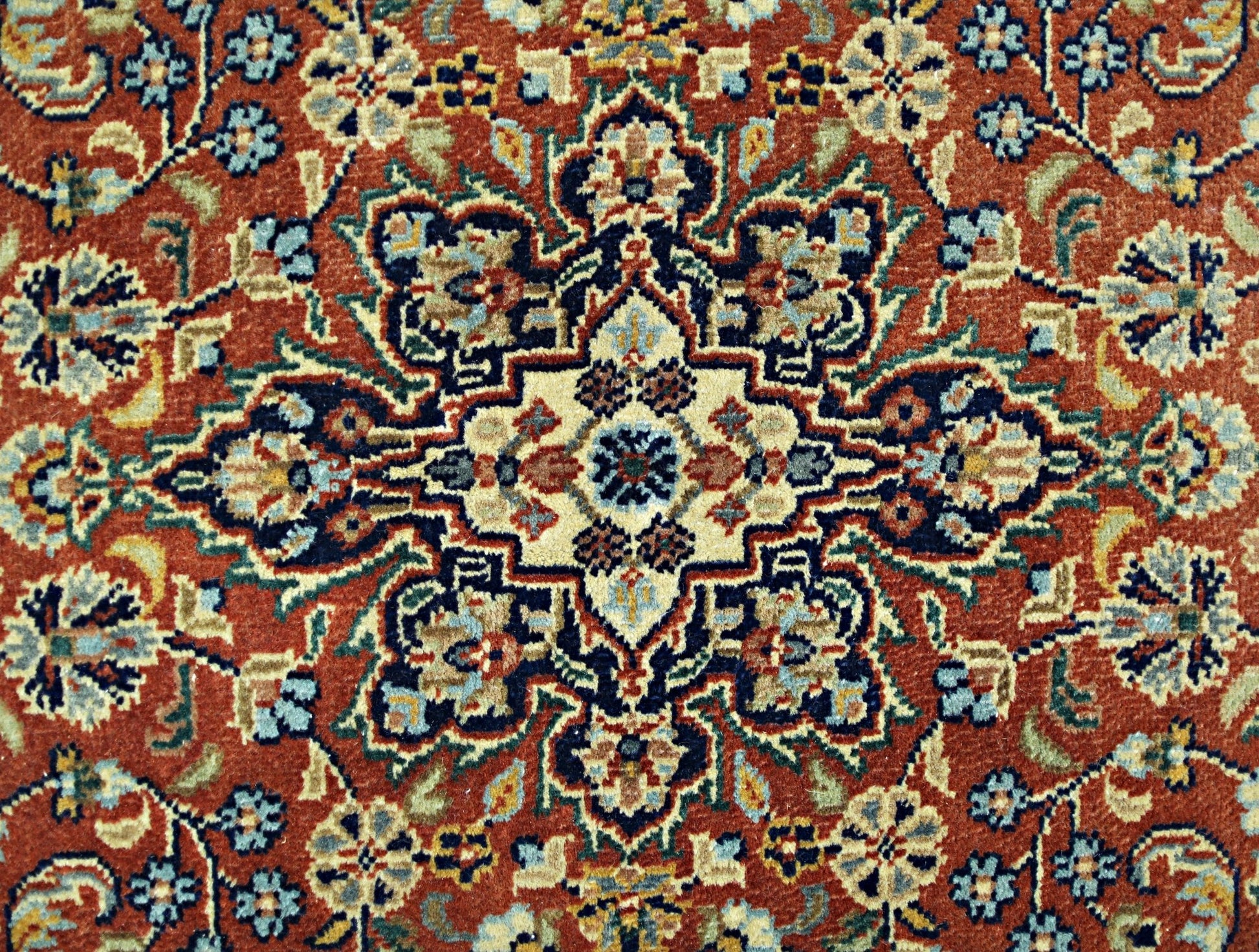 A vintage Persian rug featuring a detailed floral medallion pattern in shades of red, blue, and cream.