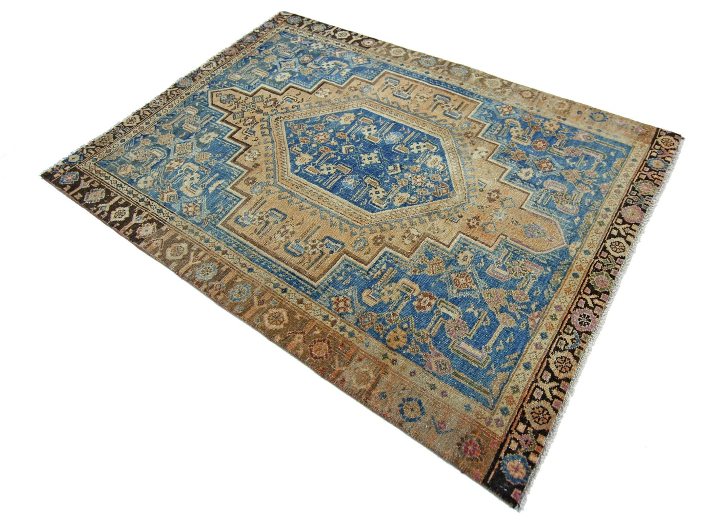A vintage Persian rug featuring a central blue medallion on a tan field with intricate patterns.