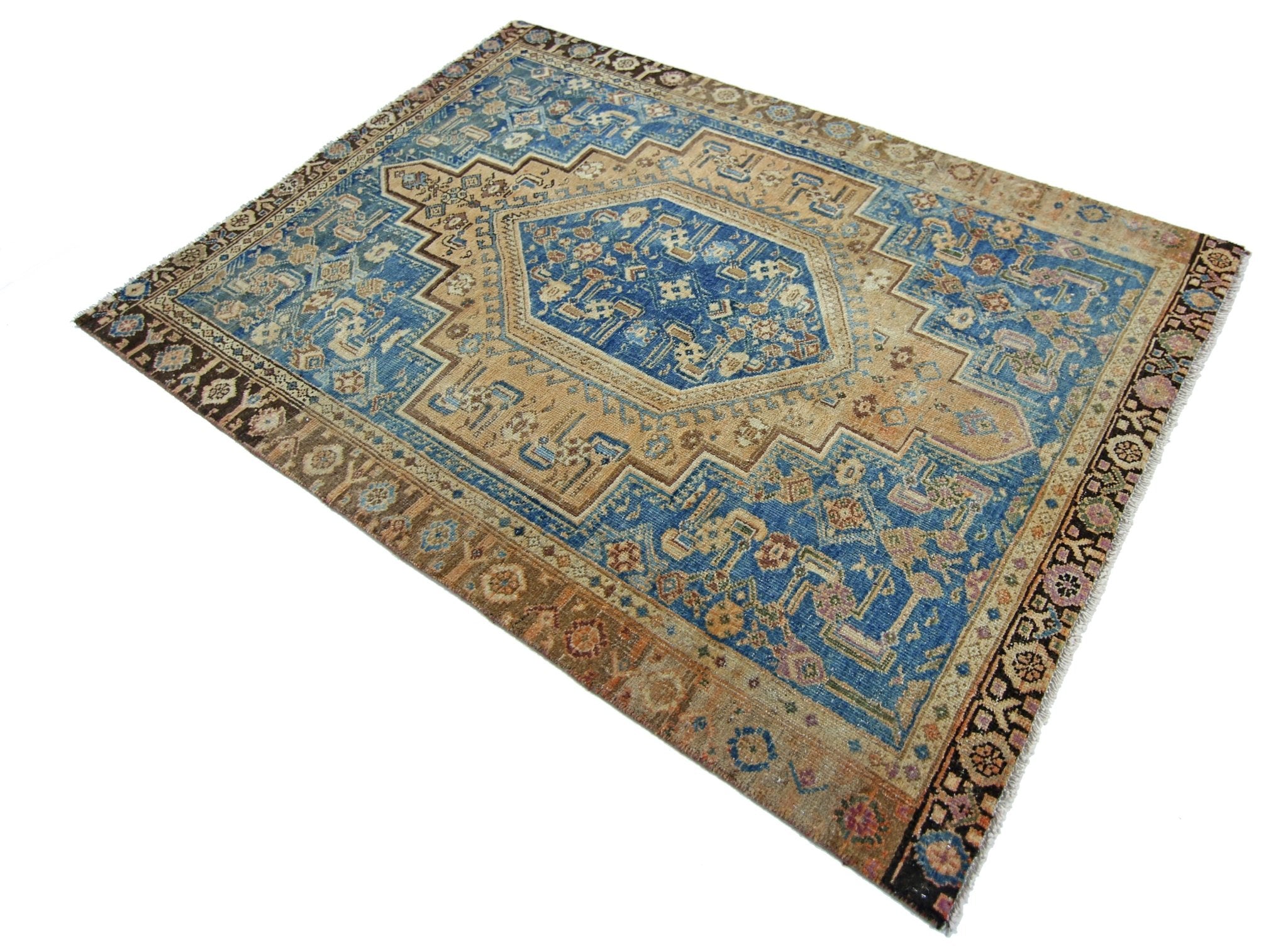 A vintage Persian rug featuring a central blue medallion on a tan field with intricate patterns.