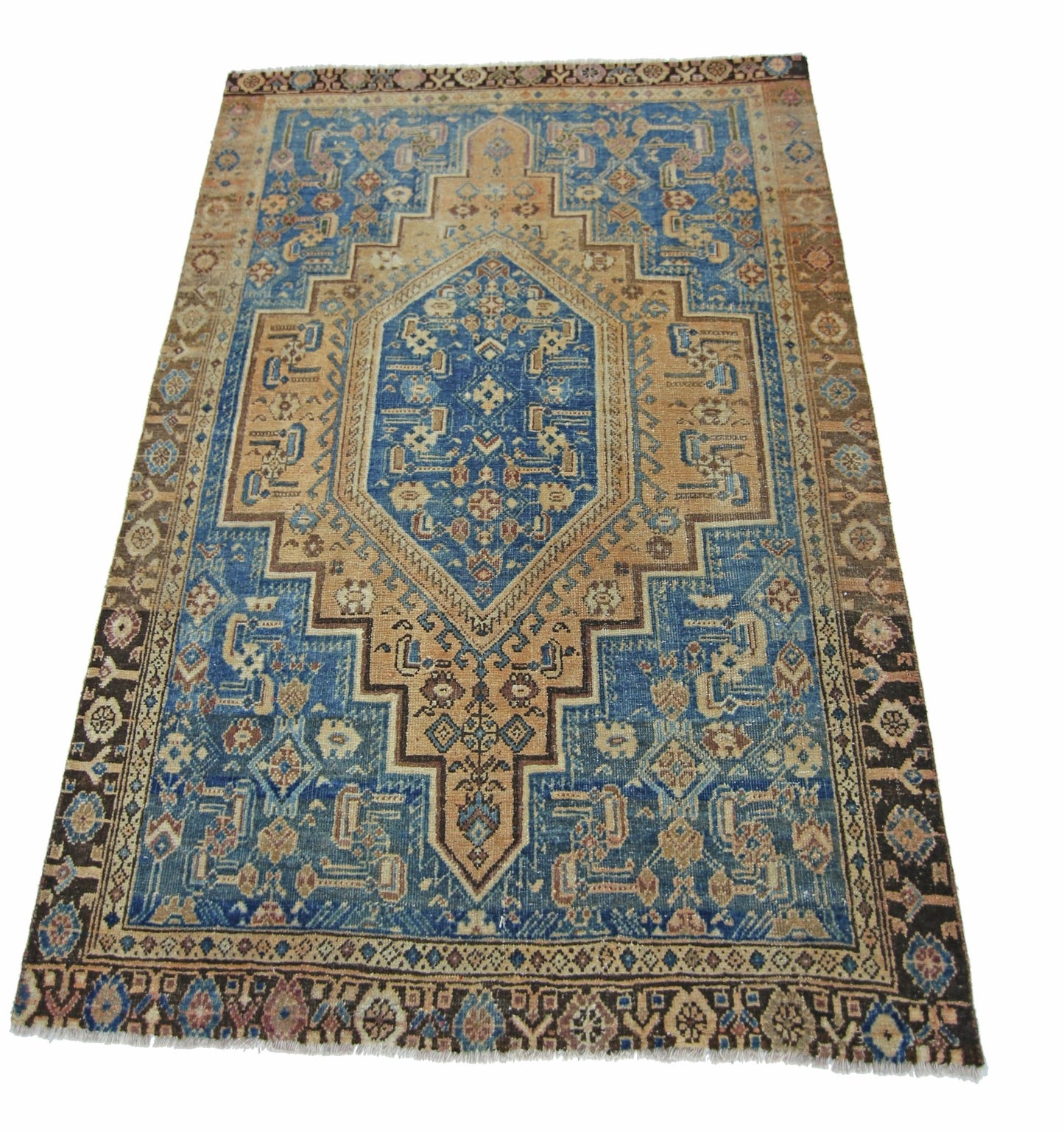 A vintage handmade Persian rug featuring a blue and tan geometric medallion pattern.