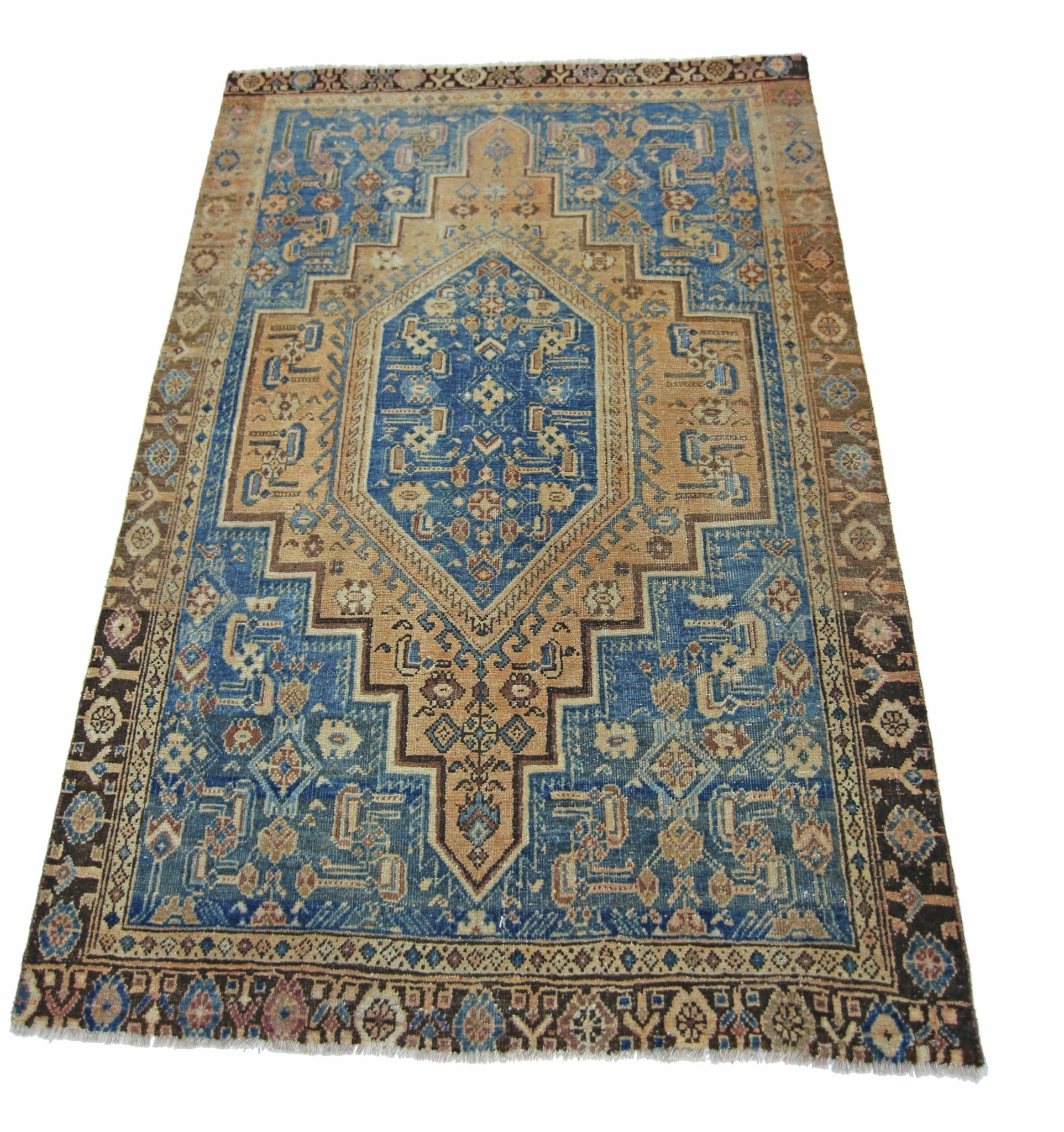A vintage handmade Persian rug featuring a blue and tan geometric medallion pattern.