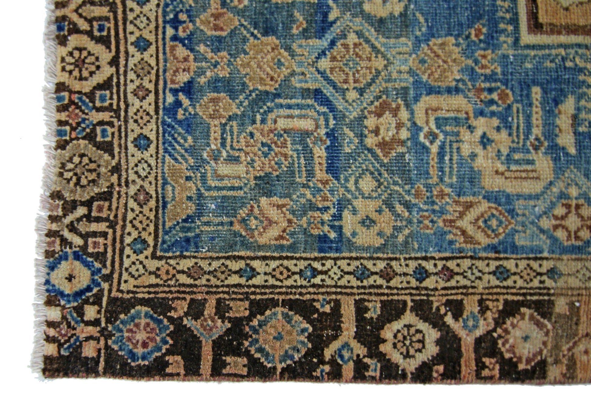 A vintage handmade Persian rug featuring intricate floral patterns in blue, brown, and beige tones.