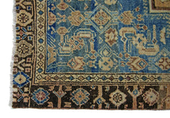 A vintage handmade Persian rug featuring intricate floral patterns in blue, brown, and beige tones.