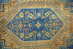A vintage Persian rug featuring a central blue diamond medallion with intricate geometric patterns.