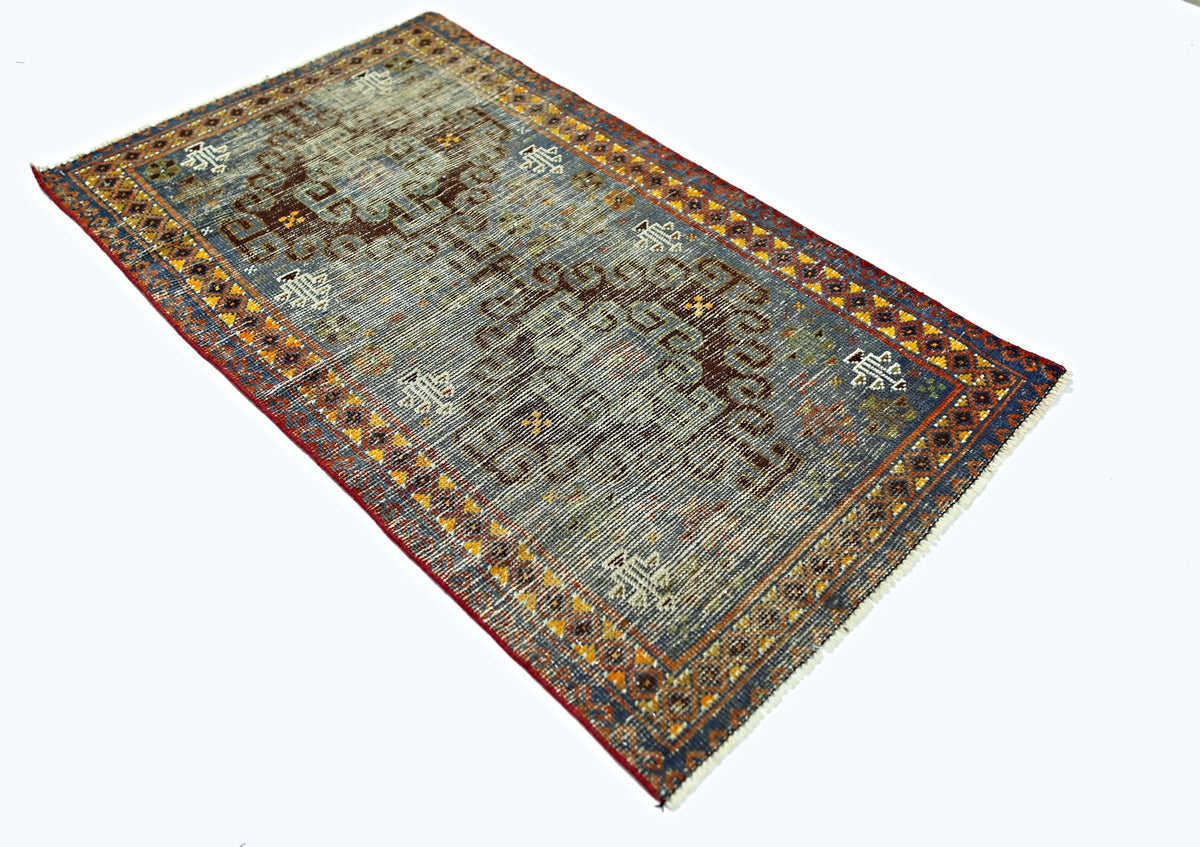 A vintage handmade Persian rug featuring a faded blue field with brown geometric motifs.