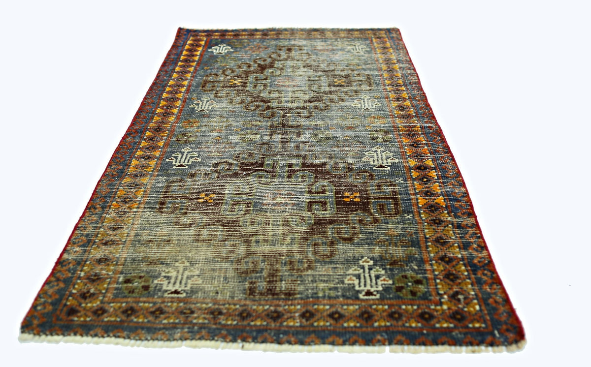 A vintage handmade Persian rug featuring a geometric pattern in blue, brown, and orange tones.
