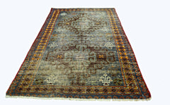 A vintage handmade Persian rug featuring a geometric pattern in blue, brown, and orange tones.