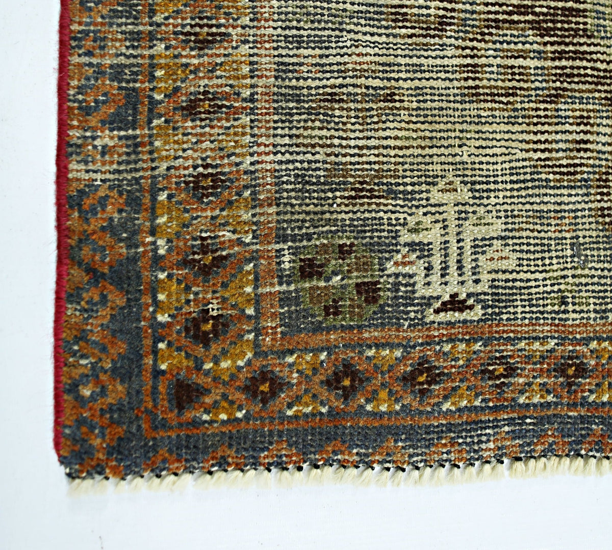A corner view of a vintage handmade Persian wool rug featuring intricate geometric patterns.