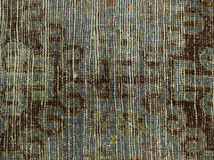 A close-up of a vintage Persian rug featuring intricate geometric patterns in brown and blue tones.
