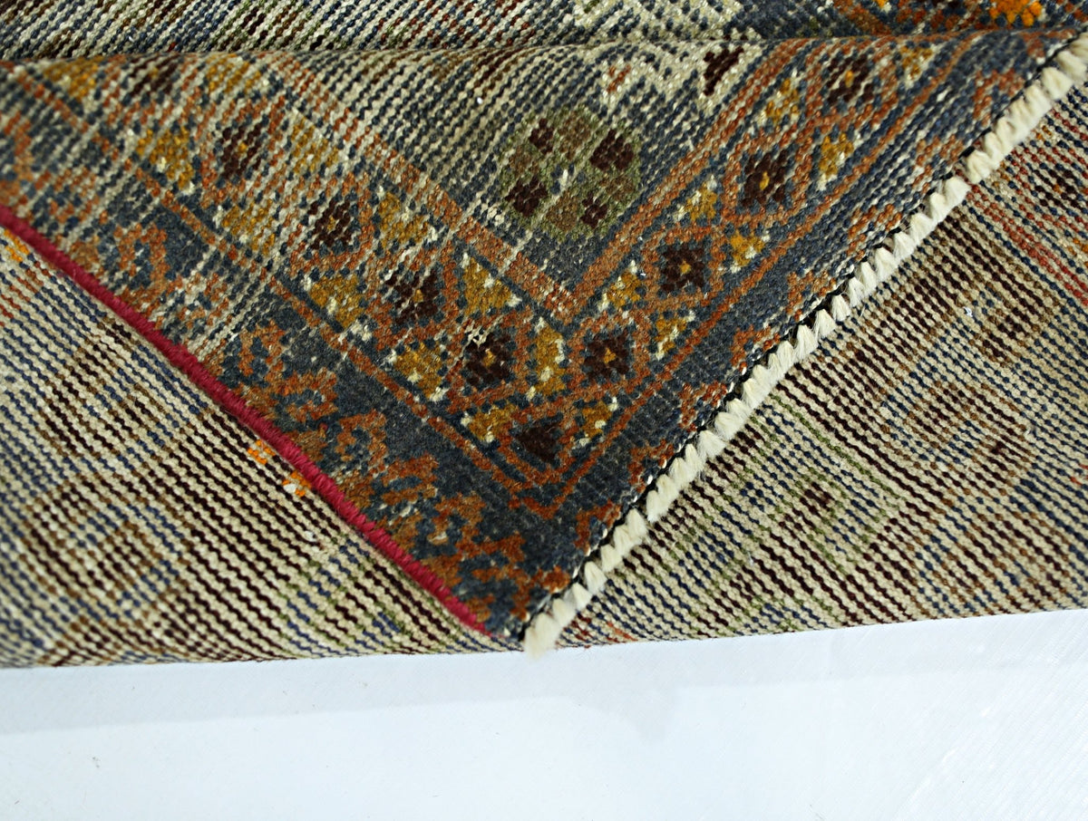 A folded vintage Persian rug featuring intricate geometric patterns in wool on a cotton base.