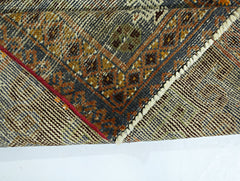 A folded vintage Persian rug featuring intricate geometric patterns in wool on a cotton base.